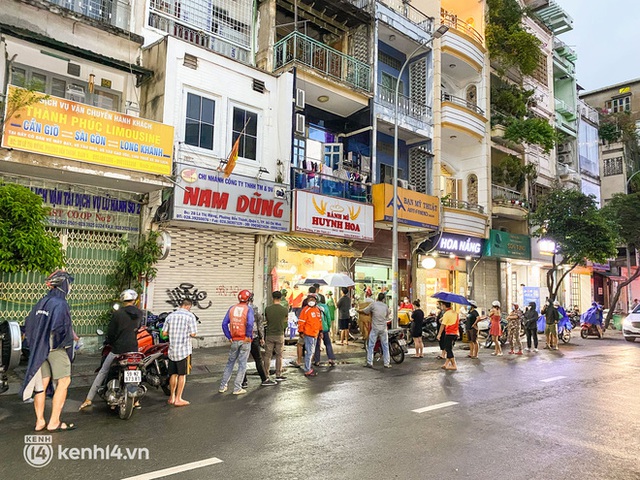 Hàng chục người xếp hàng dưới mưa mua ổ bánh mì đắt nhất Sài Gòn, có khách hốt chục cái ăn trả thù mùa dịch! - Ảnh 1.